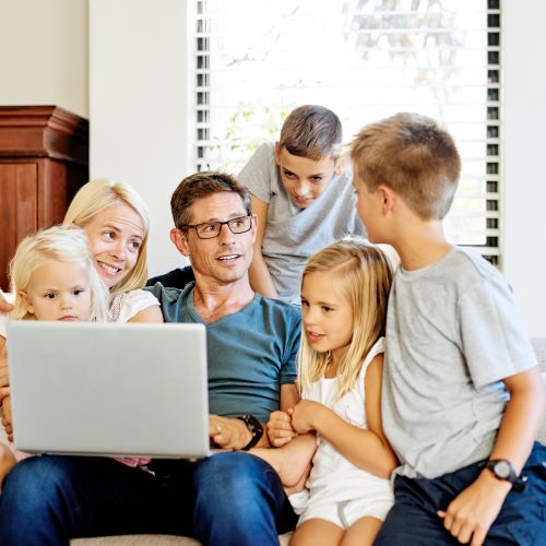 family gathered with father holding a laptop
